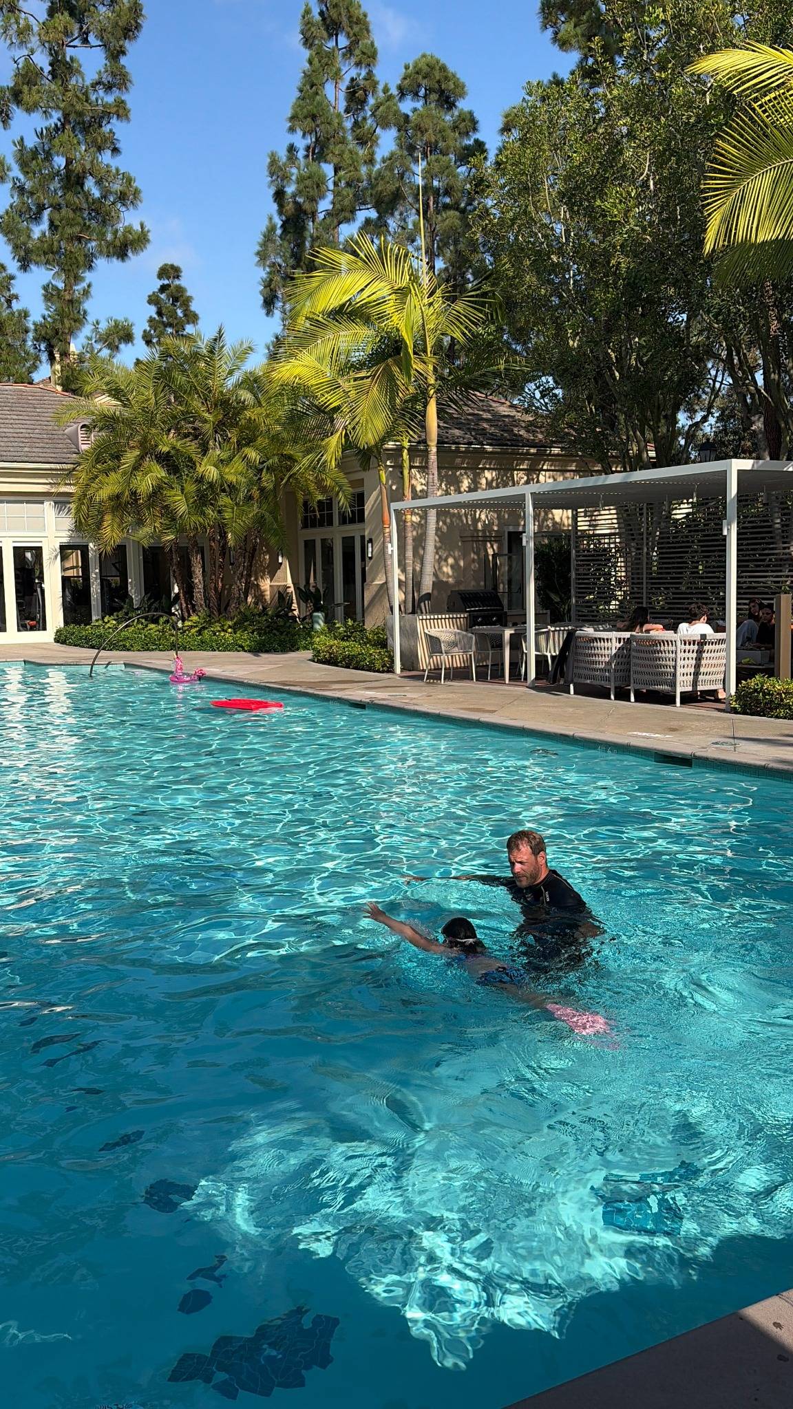 Instructor guiding a child during a private swim lesson in a sunny Orange County pool